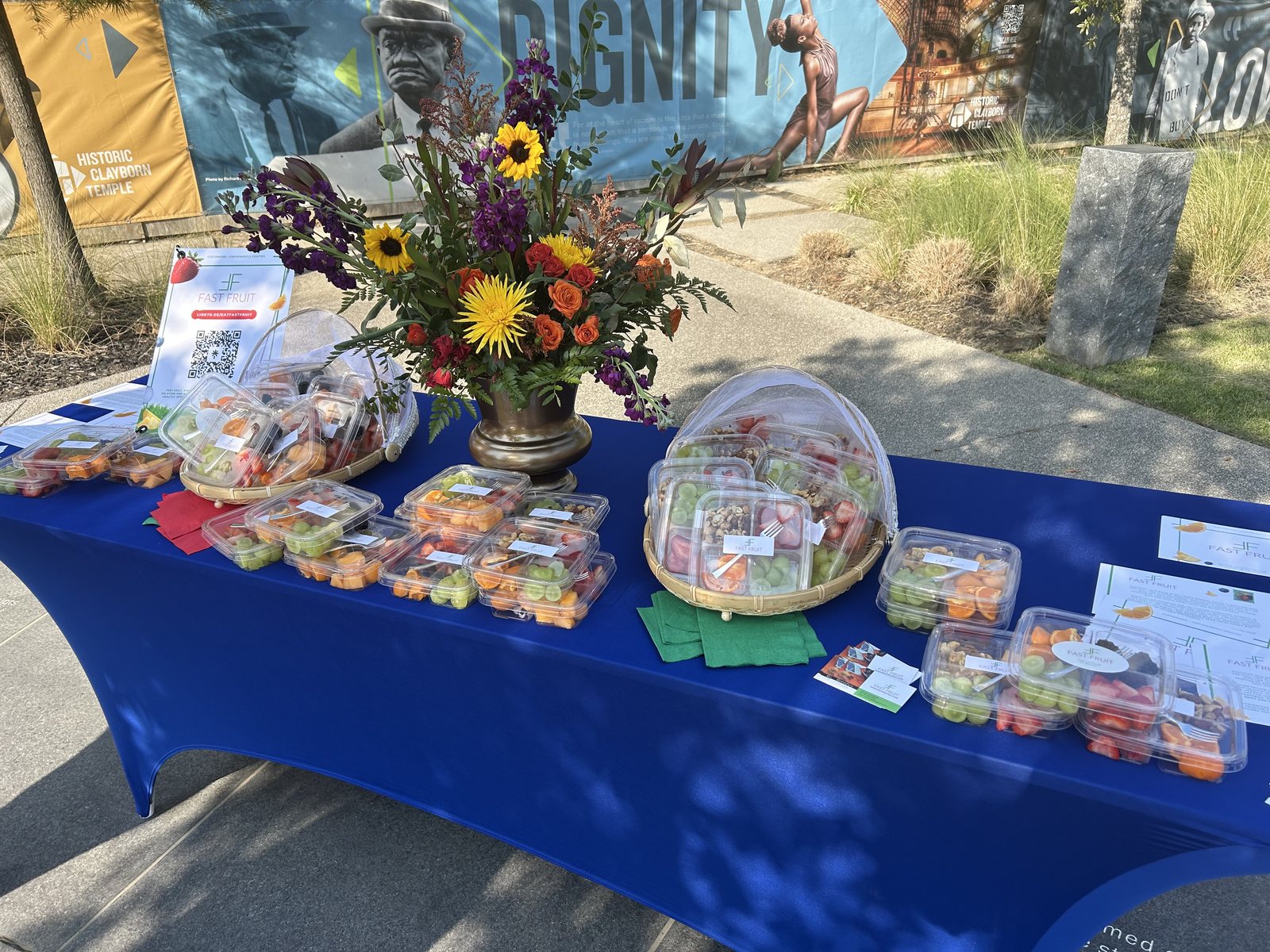 Fast Fruit community activation table displaying packaged fruit containers, flowers, and branded materials near Historic Clayborn Temple in Memphis.